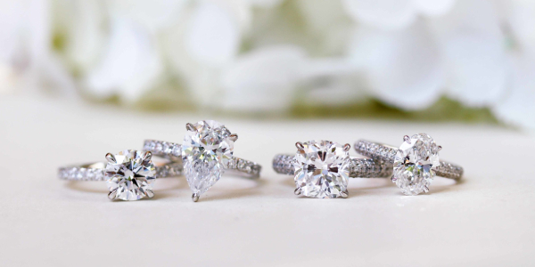 Two Pair of Diamond Rings Displayed On a White Table.